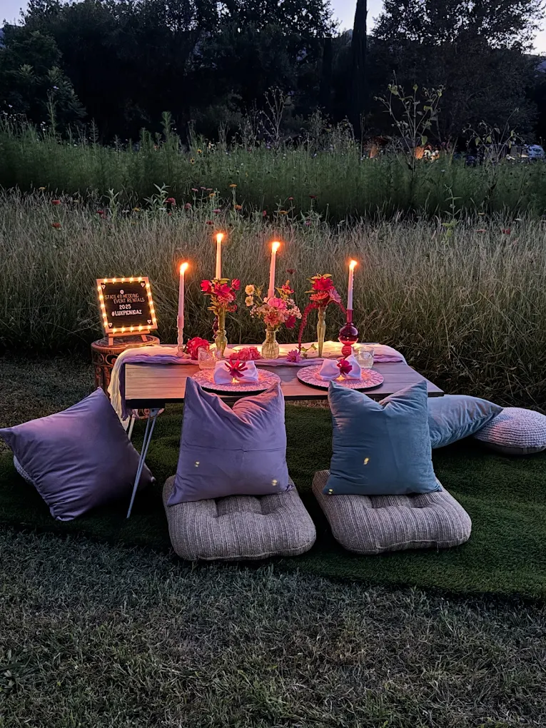 Twilight luxury picnic in wildflower meadow with marquee sign and candlelight