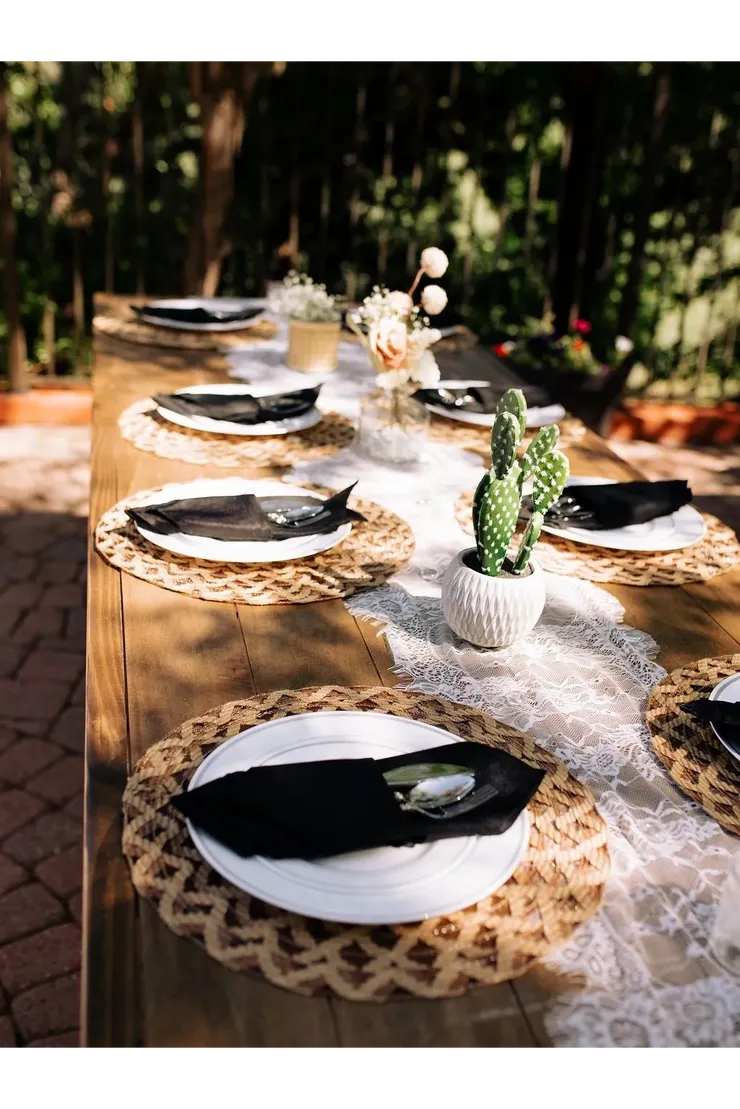 Outdoor wood table with woven chargers, black napkins and cactus accent