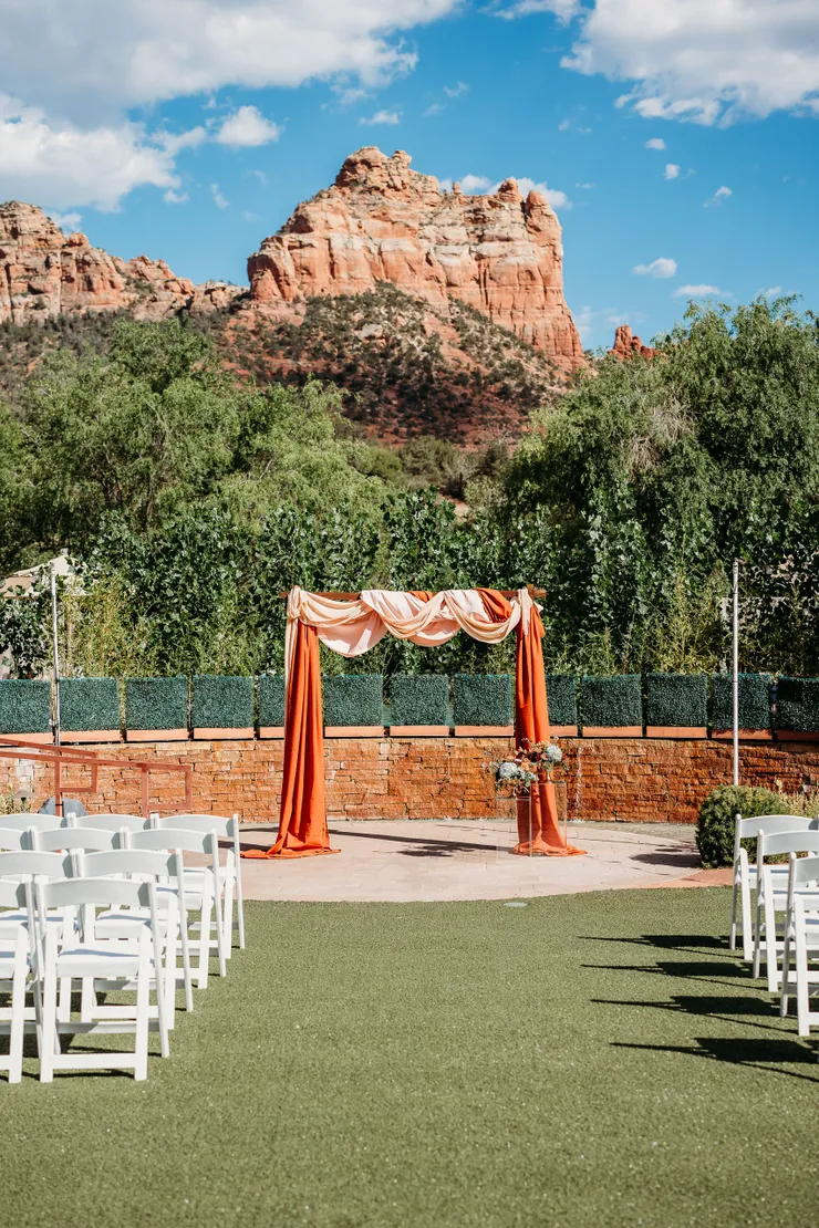 Sedona wedding ceremony arch with terracotta draping under red rocks